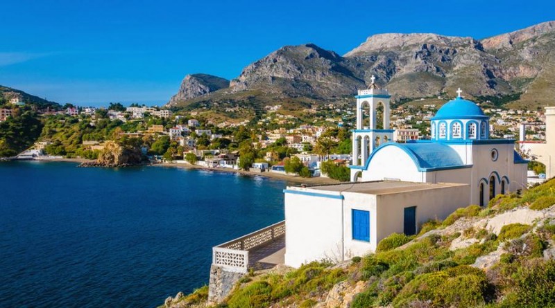 Typical for Greece white church with azure-blue dome with peacful bay in the background on Kalymnos Island, Greece